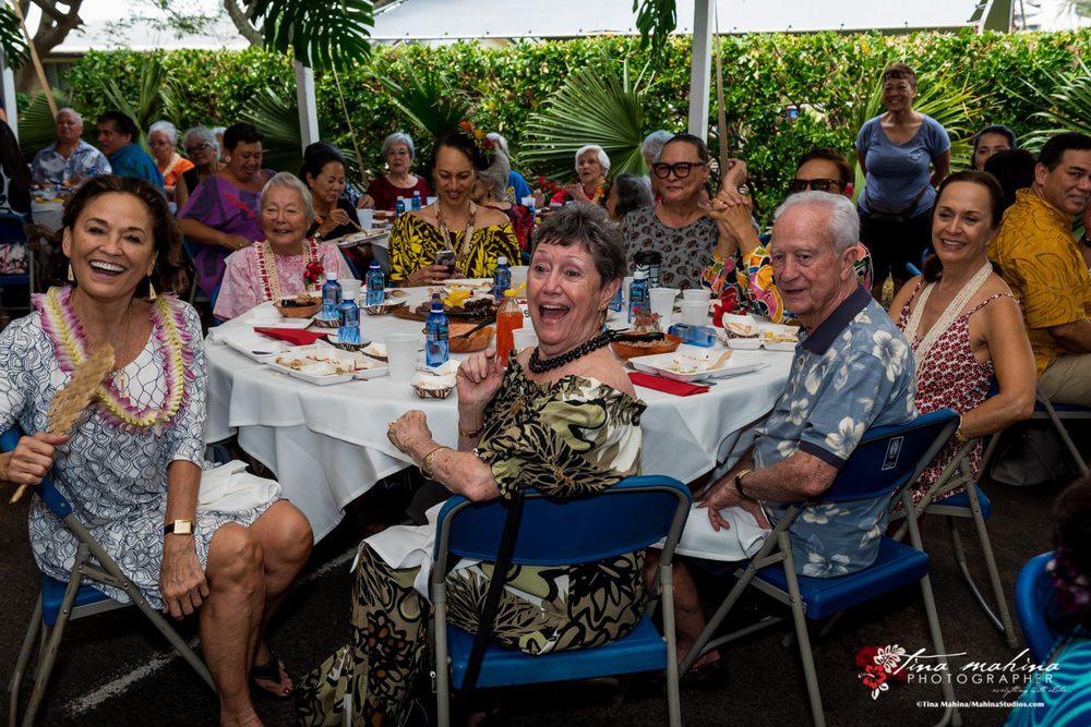 A group of people enjoying a festive gathering outdoors, surrounded by lush greenery.
