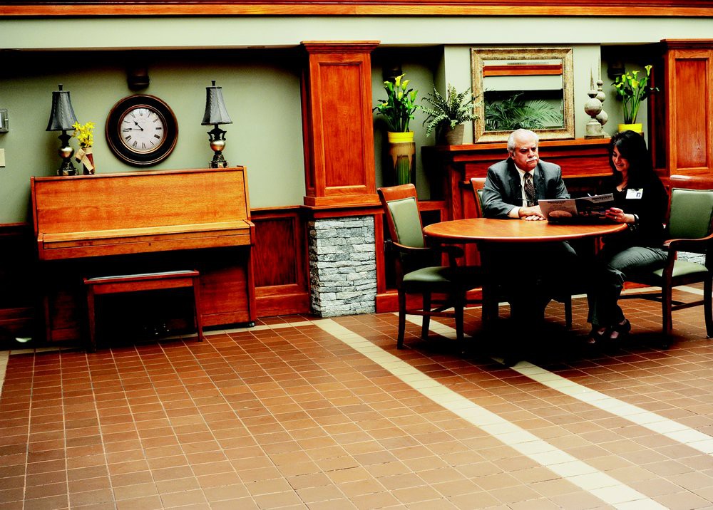 A businessman sits alone at a desk in an office waiting area.