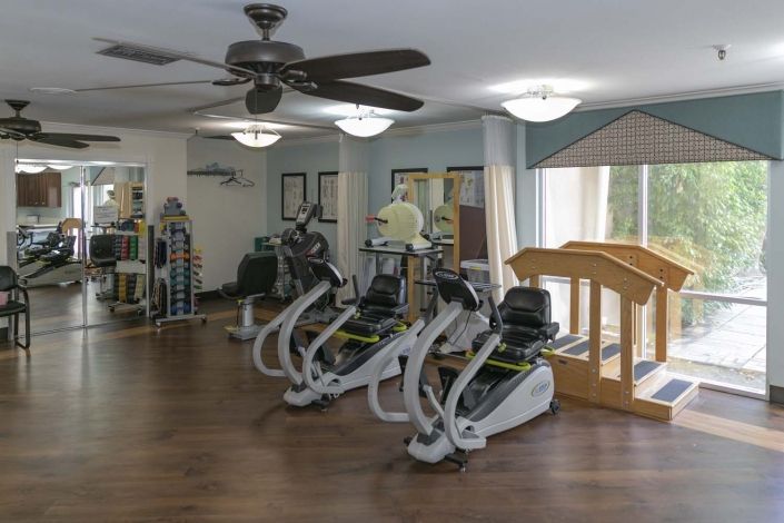 A well-lit fitness center featuring stationary bikes and various exercise equipment.