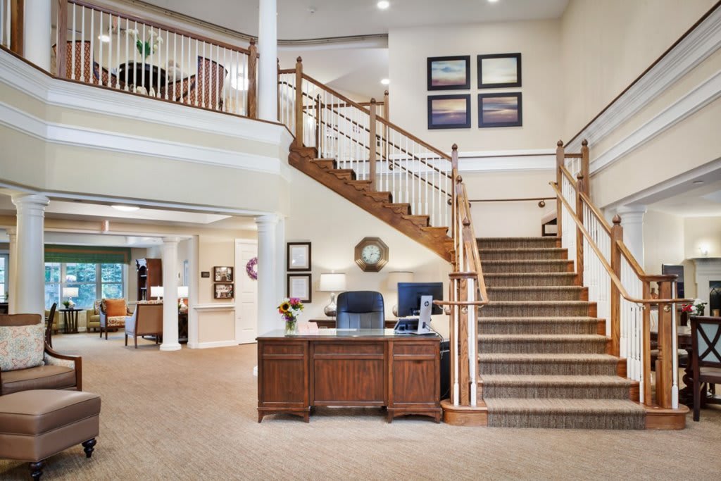 A welcoming lobby with a reception desk and staircase, featuring elegant interior design.