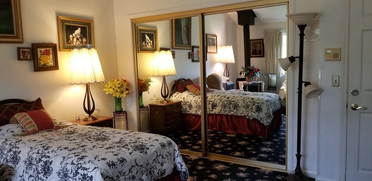 A cozy bedroom with mirrored closets, floral bedding, and warm lighting.