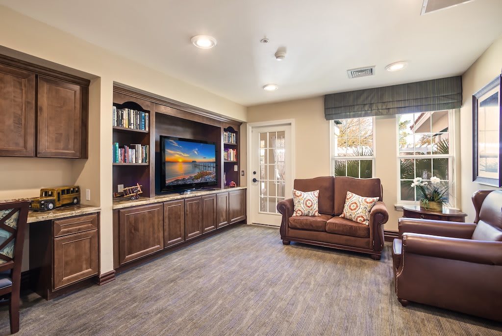 A cozy living room with a large television, bookshelves, and comfortable seating.