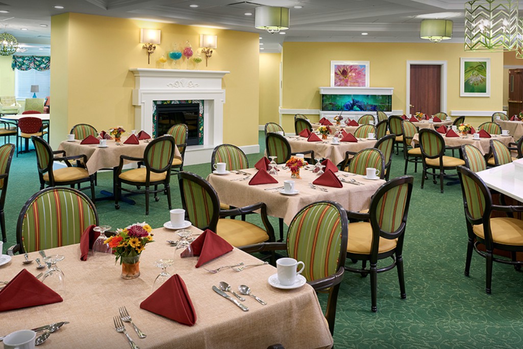 An elegant dining room with neatly set tables and chairs, featuring a cozy fireplace.