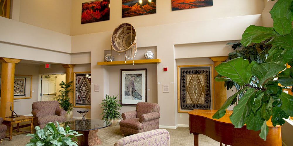 A cozy lobby area featuring armchairs, decorative artwork, and plants.