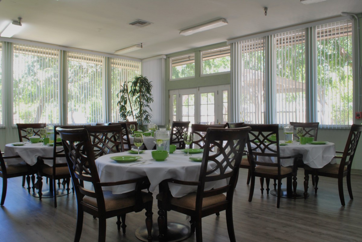 A well-lit dining area with neatly arranged tables and chairs, featuring large windows allowing natural light to fill the room.