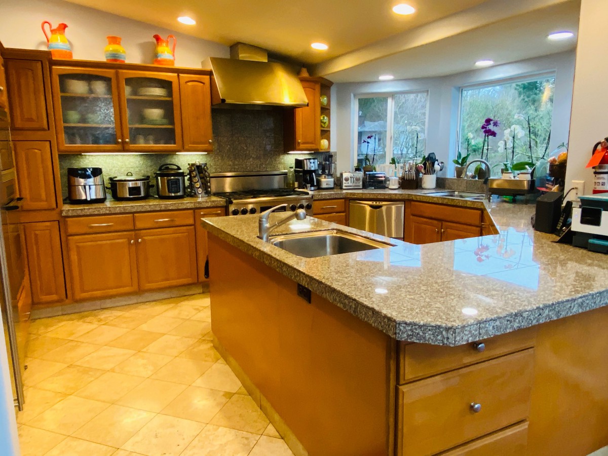 A modern kitchen with an island, featuring wood cabinets and various appliances.