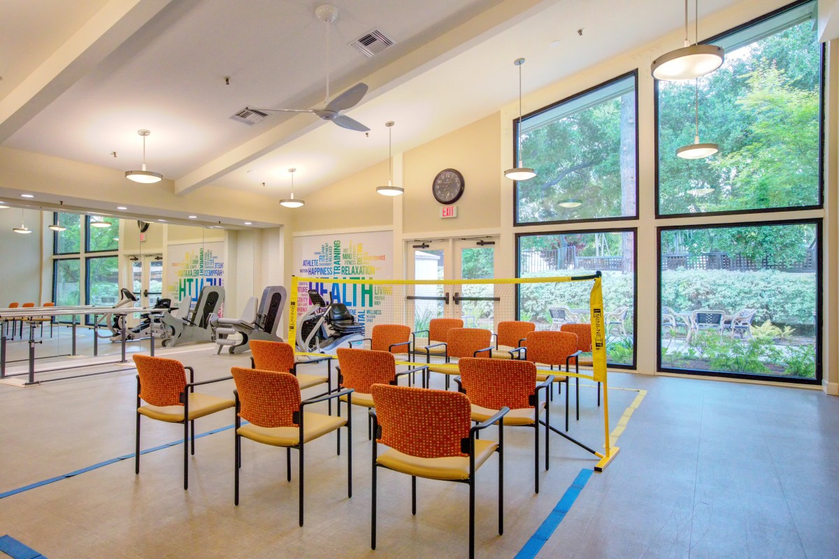 A well-lit fitness center with exercise equipment and a seating area.