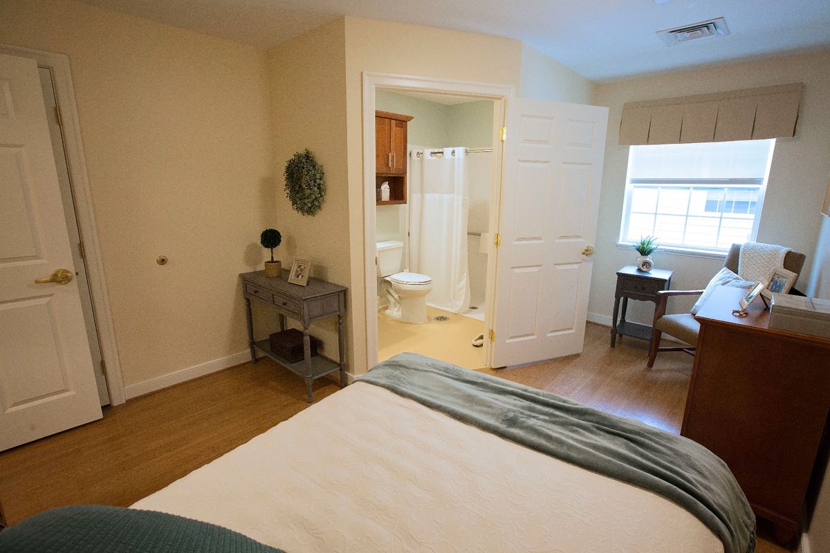 A cozy bedroom with an attached bathroom, featuring simple decor and comfortable furnishings.