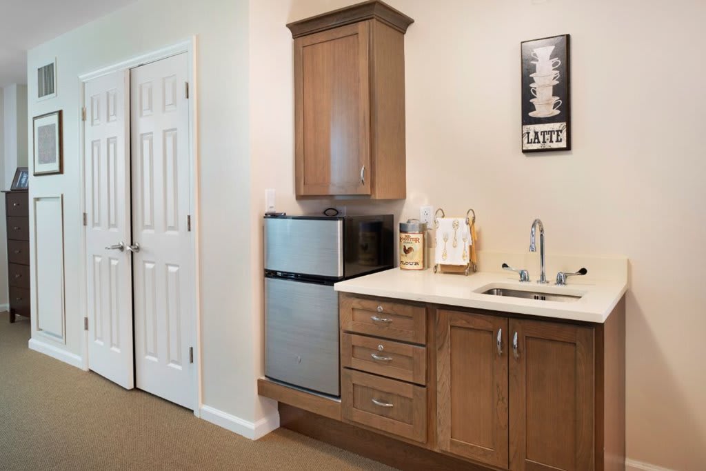 A compact kitchenette featuring a mini fridge, microwave, and cabinetry with a small sink area.