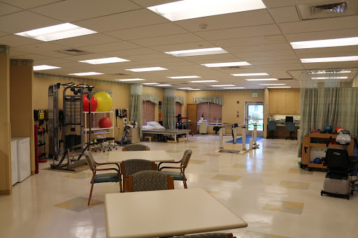 An interior view of a spacious rehabilitation therapy room equipped with exercise gear and bright lighting.