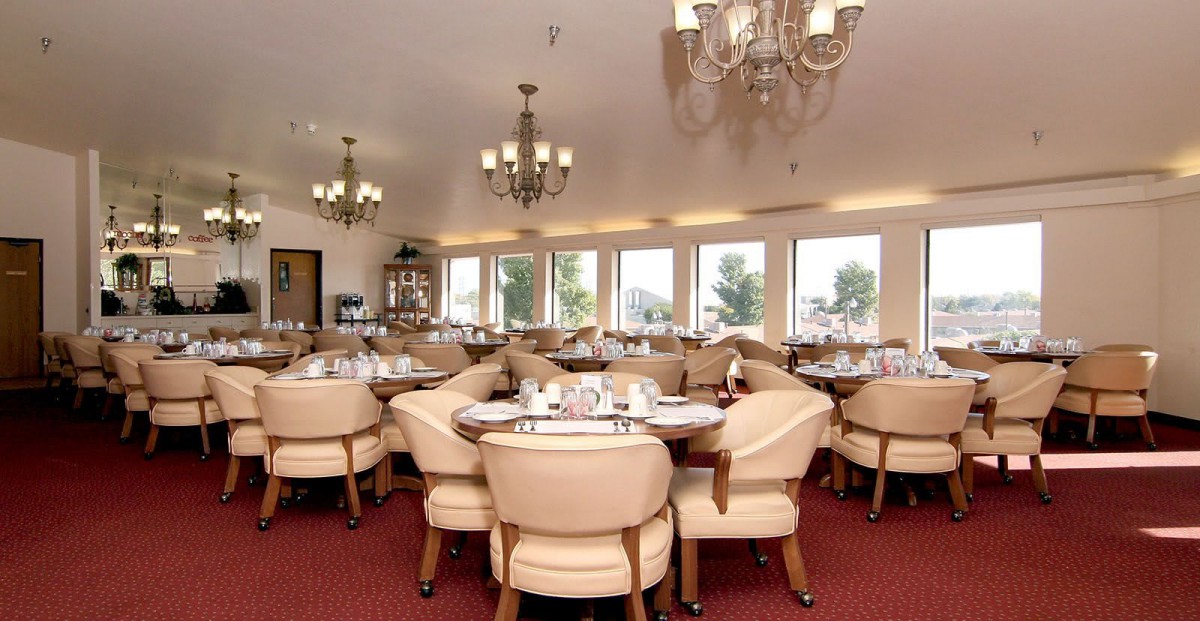 A spacious restaurant dining area with elegant chandeliers and neatly arranged tables.