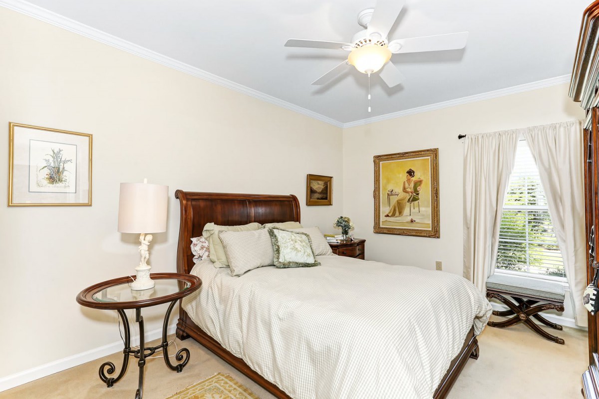 A cozy bedroom with a wooden bed, decorative pillows, and framed artwork on the walls.