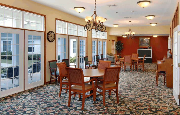 A bright, well-furnished dining area with tables and chairs arranged neatly under warm chandeliers.