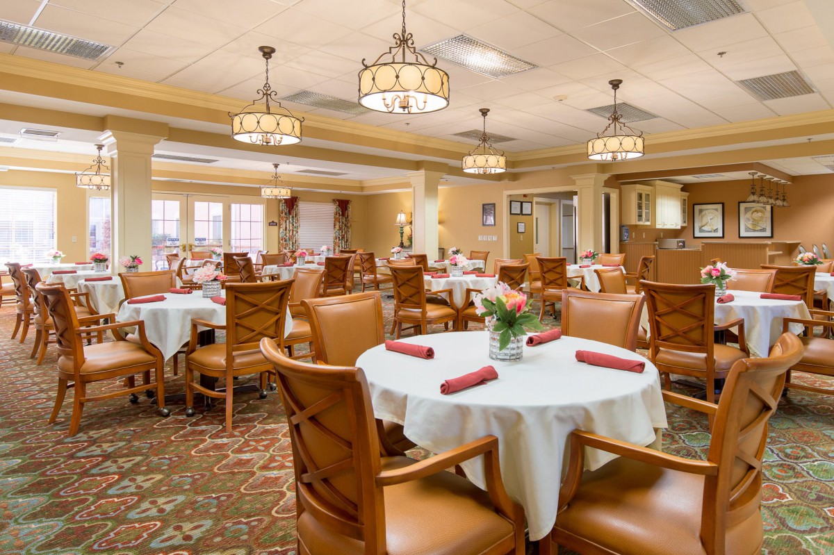 An elegant dining room with neatly arranged tables and chairs, featuring warm lighting and decor.