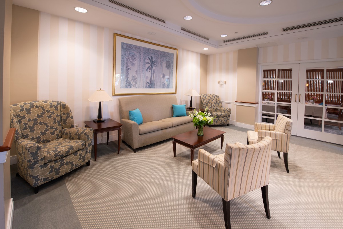 A cozy living room with sofas, chairs and a coffee table, featuring elegant decor and wall artwork.
