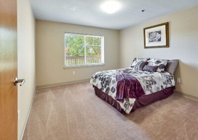 A cozy bedroom featuring a bed with patterned bedding and a window offering natural light.