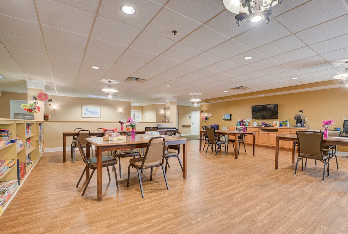 A spacious dining area with tables and chairs, featuring a television on the wall and decorative lighting.