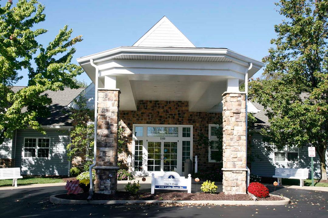 A building entrance featuring stone columns and a landscaped front.