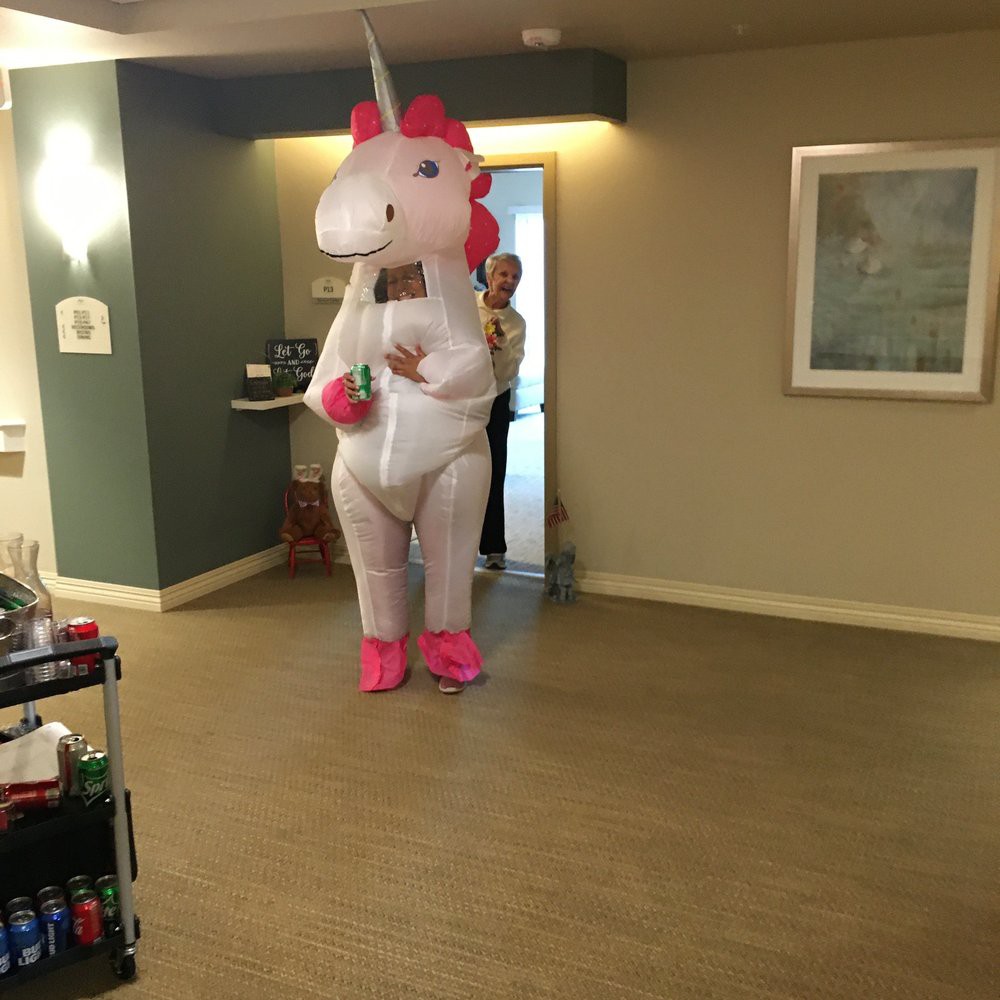 A person wearing an inflatable unicorn costume indoors.