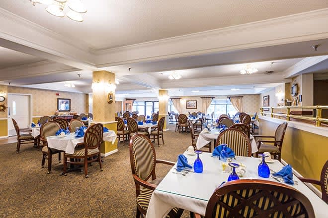 Elegant dining area with neatly arranged tables and chairs, featuring blue glassware.