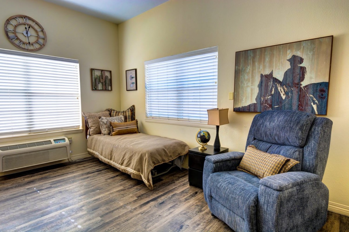Cozy bedroom with a single bed, recliner chair, and decorative artwork on the walls.