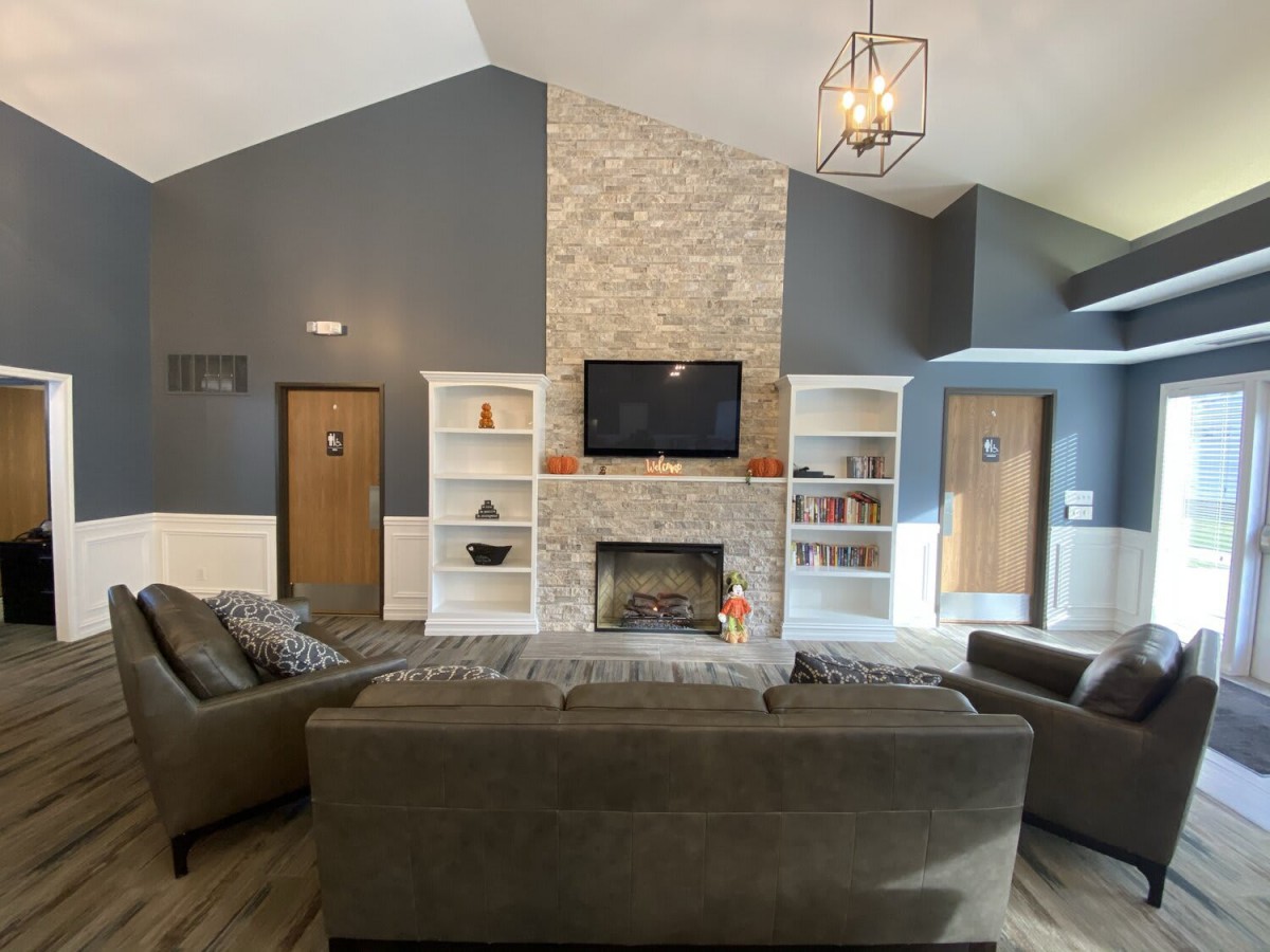 A modern living room featuring a central fireplace with flanking bookshelves, comfortable sofas, and a television mounted above the mantel.