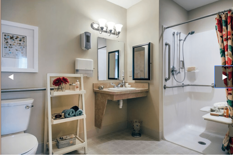 A modern bathroom with a sink, mirror, and accessible shower area.