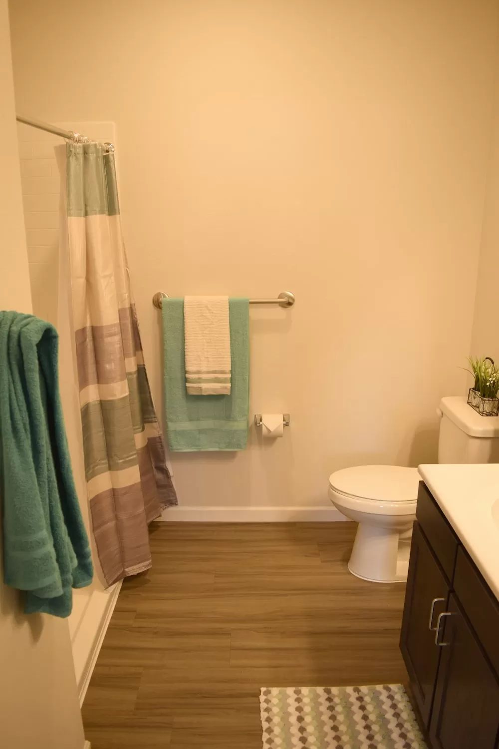 A modern bathroom with neatly arranged towels in blue and white hues, a shower curtain, and a clean toilet.