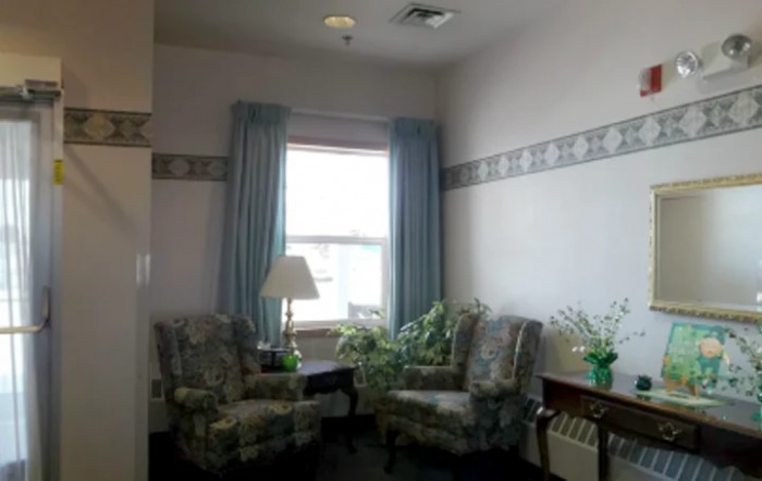 A cozy sitting area with two chairs and a lamp by the window.