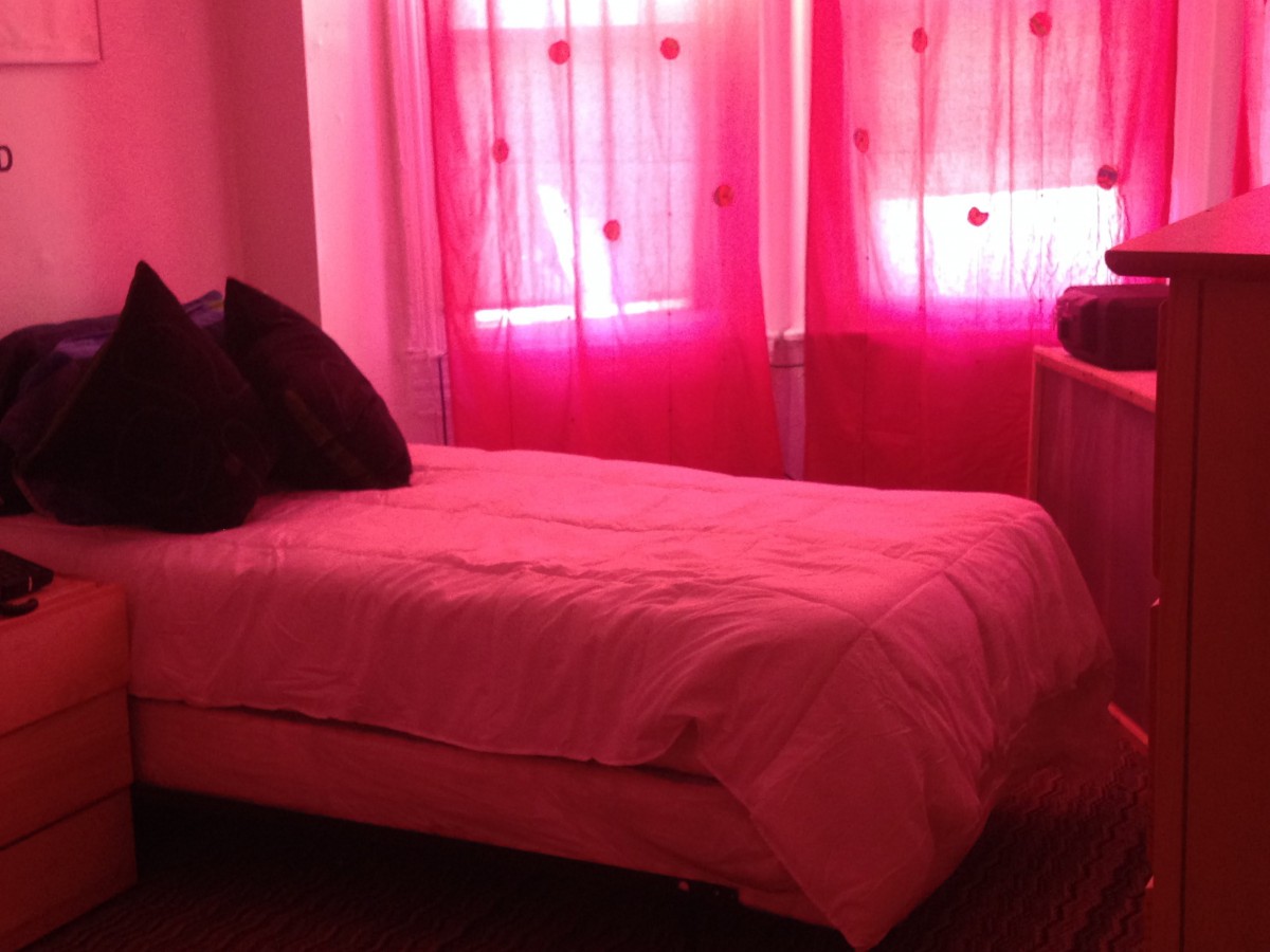 A cozy bedroom with pink curtains and bedding.