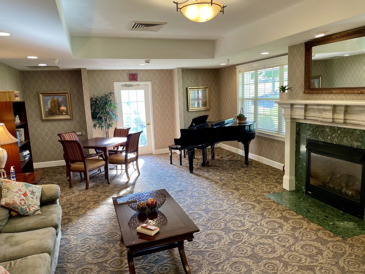 A cozy living room featuring a grand piano, comfortable seating, and a fireplace.