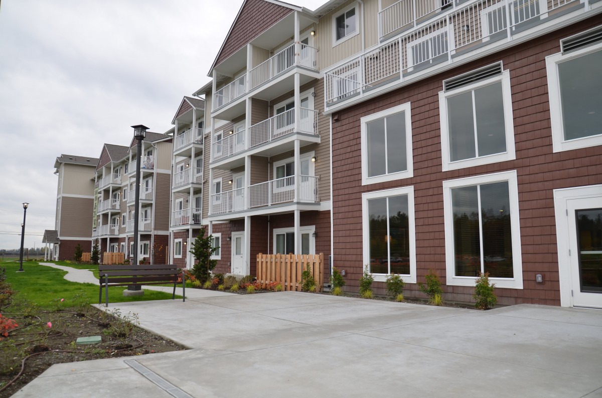 A modern residential apartment building with multiple balconies and landscaped surroundings.