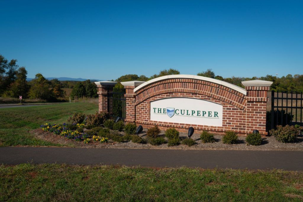 A brick sign welcoming visitors to Culpeper set against a clear blue sky.