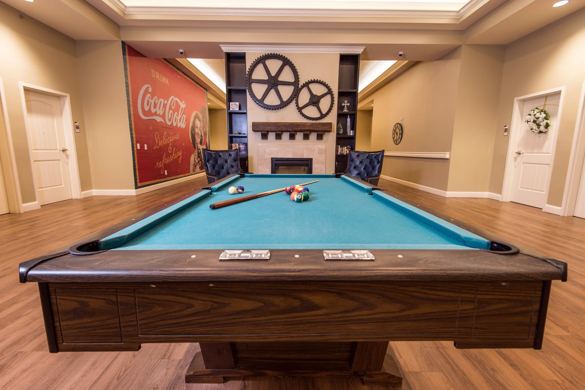 A cozy game room featuring a pool table and fireplace.