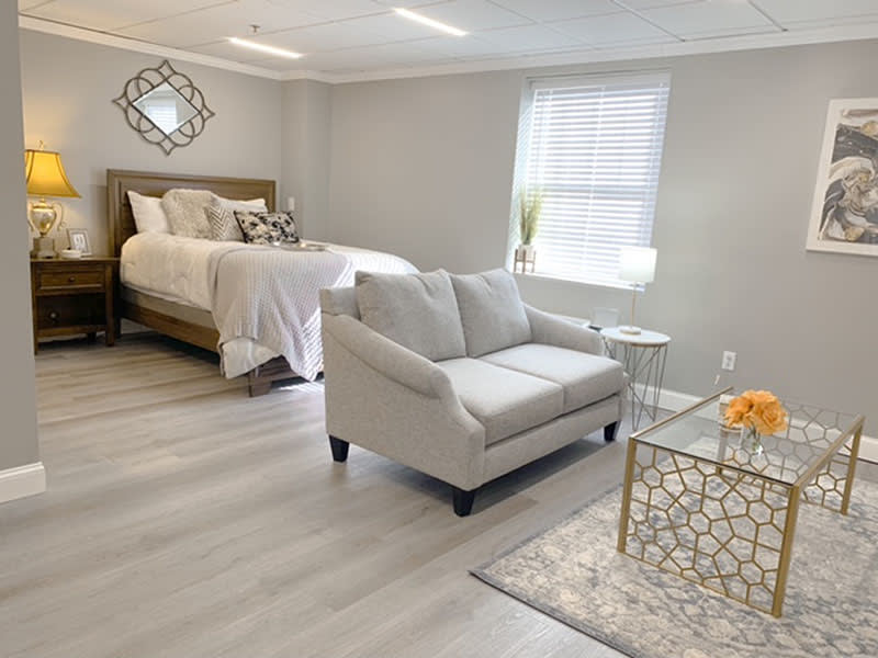 A modern and minimalist bedroom with an integrated living area, featuring a comfortable bed, a stylish sofa, and a decorative coffee table.