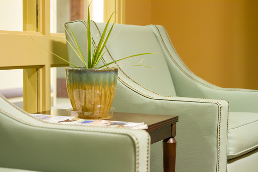 A serene corner featuring a stylish mint-green chair and a decorative plant on a side table.