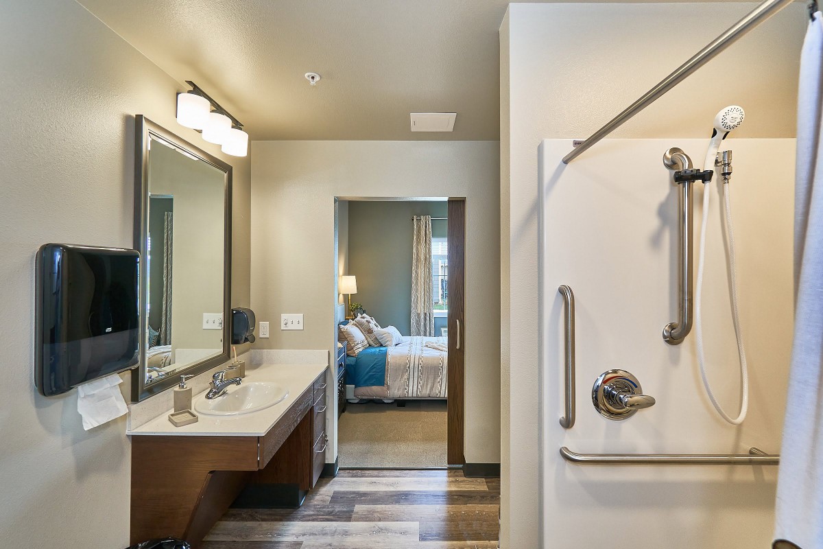 Modern bathroom with a double sink and a view into the bedroom.