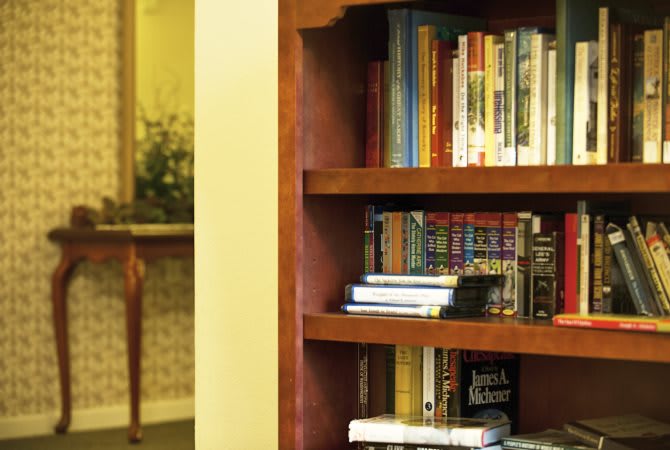 A wooden bookshelf filled with an assortment of books.