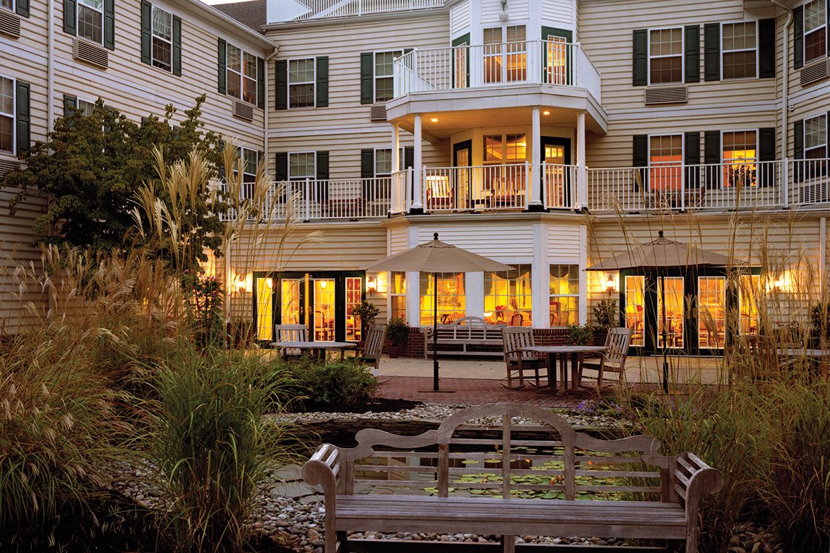 An elegantly designed hotel with glowing windows, surrounded by a peaceful garden setting in the evening.