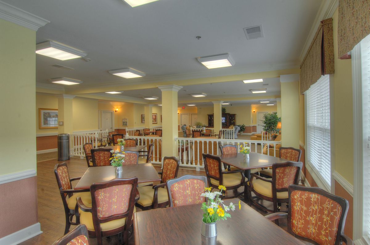 Spacious dining area with multiple tables and chairs, decorated with flowers.