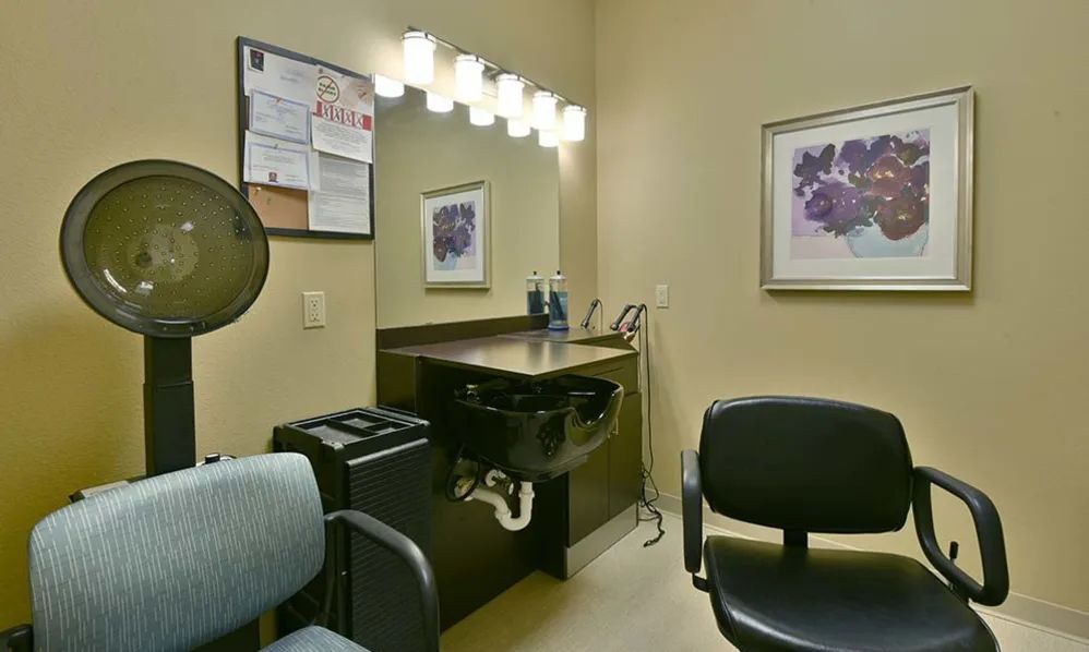 A cozy hair salon interior featuring a mirror, chairs, and wash station with warm lighting.