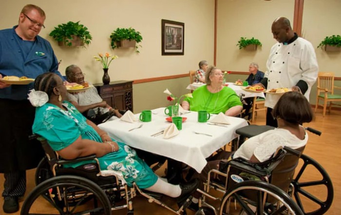 Elderly residents enjoying a meal together in a nursing home's dining area.