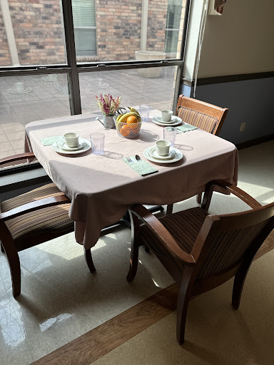 A neatly arranged dining table by the window, adorned with a fruit centerpiece.