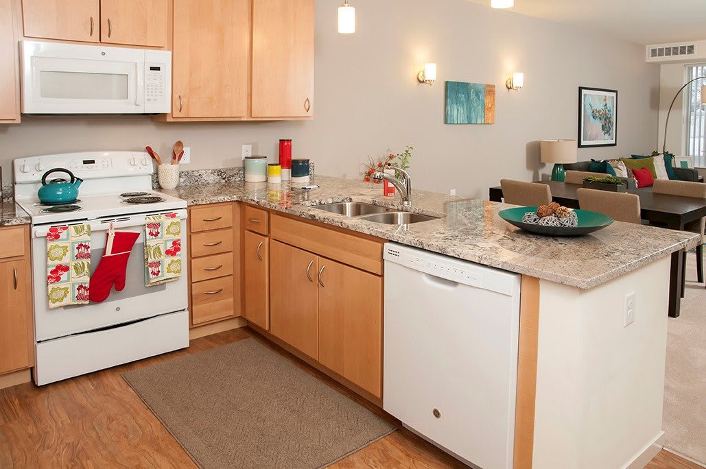 A modern kitchen with wooden cabinets, white appliances, and a marble countertop.