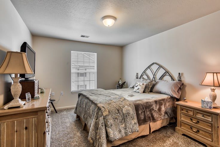 A cozy bedroom with a neatly made bed and natural light coming through the window.