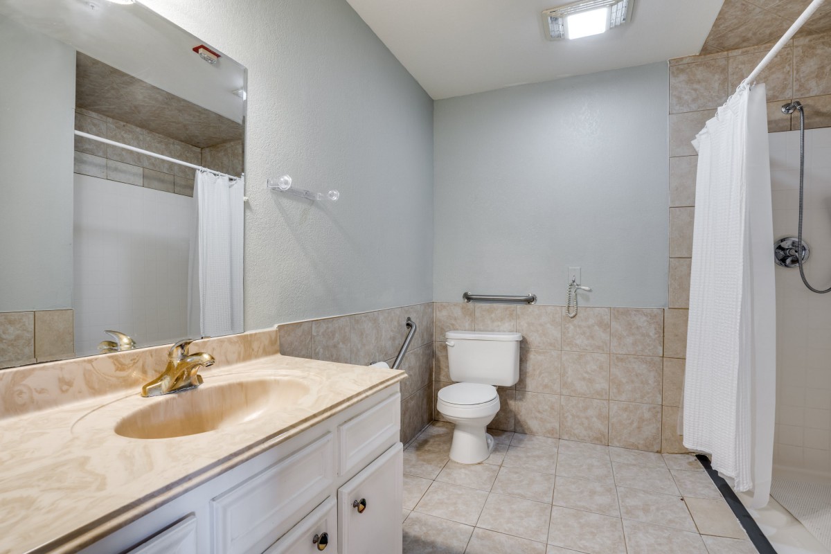 A clean and simple bathroom with tiled walls, a sink, and a mirror.