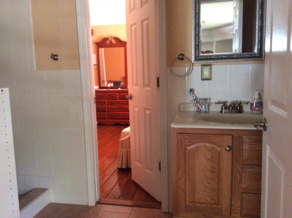 A view from a bathroom looking into an adjacent bedroom with a dresser.