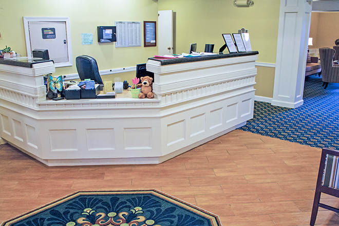 A well-lit reception area with a wooden desk and patterned carpet.