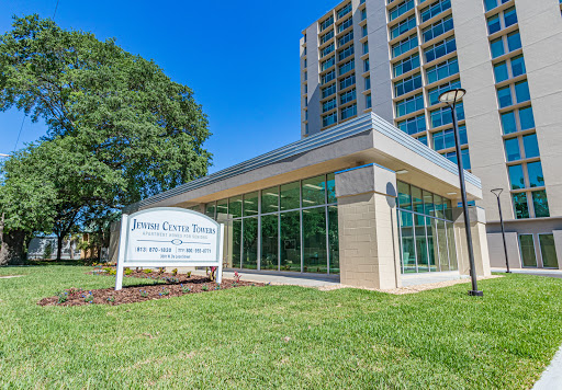 A modern building featuring large glass windows and a welcoming entrance, surrounded by lush green grass.