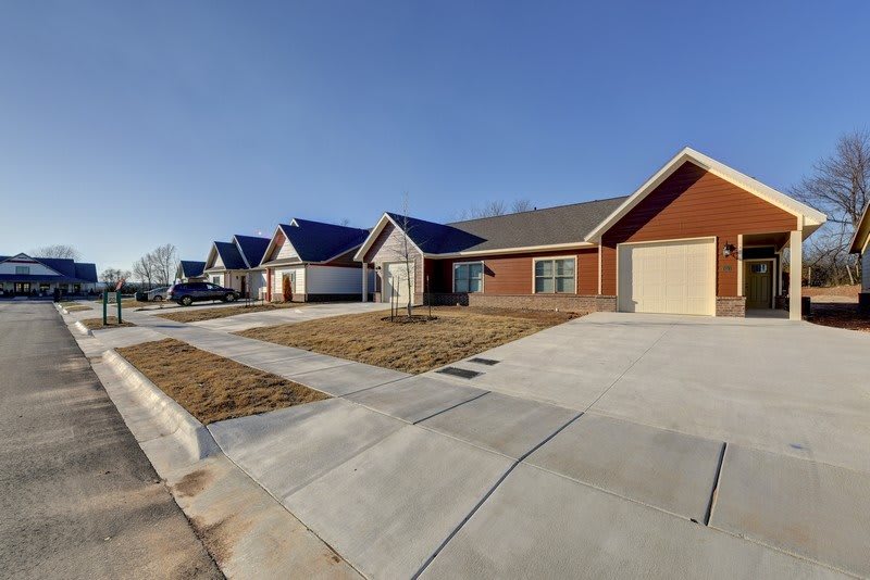 A row of modern suburban houses with spacious driveways under a clear blue sky.